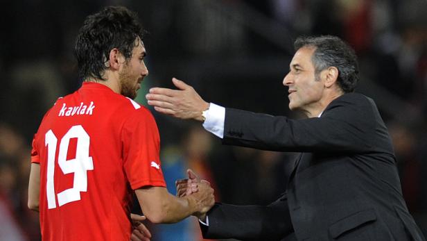 Ein Fußballspieler mit der Nummer 19 gibt einem Mann im Anzug die Hand.