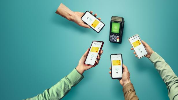 Mehrere Hände halten Smartphones für eine kontaktlose Zahlung neben einem Kartenlesegerät.