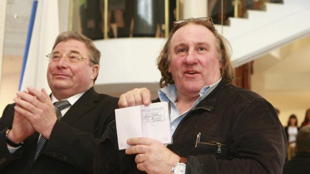 REFILE - CORRECTING DATE French film star Gerard Depardieu (R) shows his passport with residency permit as Vladimir Volkov, head of the Republic of Mordovia, applauds during a visit to the town of Saransk, southeast of Moscow February 23, 2013. REUTERS/Yulia Chestnova (RUSSIA - Tags: POLITICS PROFILE ENTERTAINMENT)