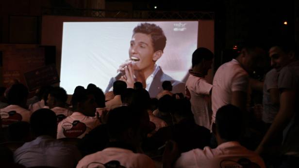 epa03725700 Fans of Palestinian singer Mohammad Assaf watch him on a huge screen as he performs in the Arab Idol competition in Nablus, West Bank, 31 May 2013. Since March, the 22-year-old is Gaza&#039;s powerful voice. Palestinians watch him every weekend to the ranks of only seven remaining singers in a Beirut-based competition that started out with 27 contestants. EPA/ALAA BADARNEH