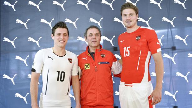 Drei Männer posieren vor einem Hintergrund mit Puma-Logos.