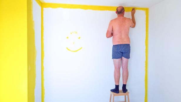 Man in underwear painting the walls of a room
