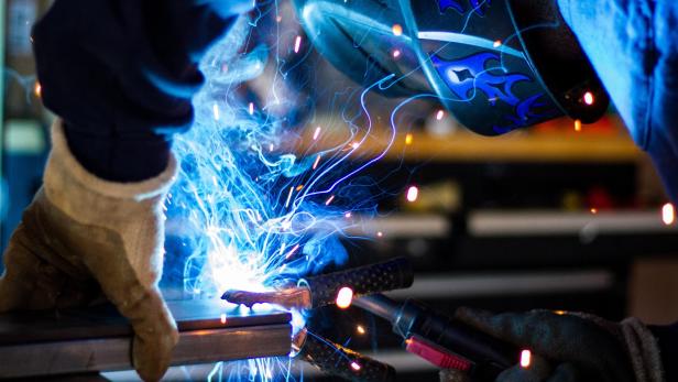 Ein Schweißer arbeitet mit Schutzkleidung an einem Metallrahmen.