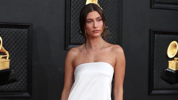 Hailey Bieber in einem weißen, trägerlosen Kleid auf dem roten Teppich.