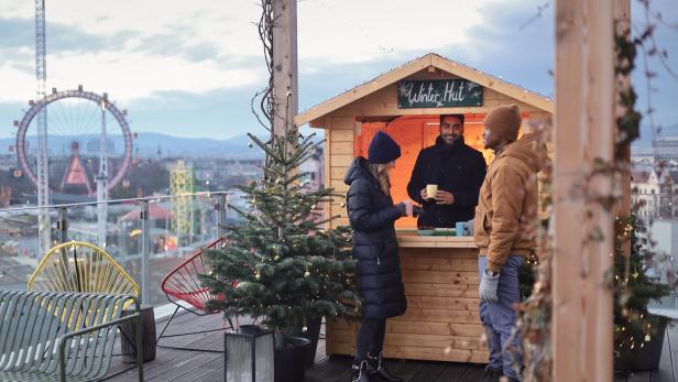 Auf einer Dachterrasse besuchen Menschen eine „Winter Hut“ mit Blick auf Wien.