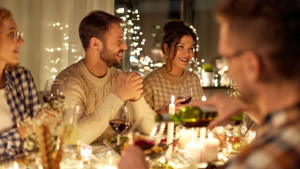 veganes Weihnachtsessen, Kerzenschein, Familie am Esstisch, Rotwein, Tischdeko
