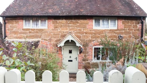 Das „Honeysuckle Cottage“ ist ein kleines Haus mit einem weißen Lattenzaun.