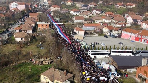 Local Serbs carry a giant Serbian flag as they protest against the government near a roadblock in Rudare