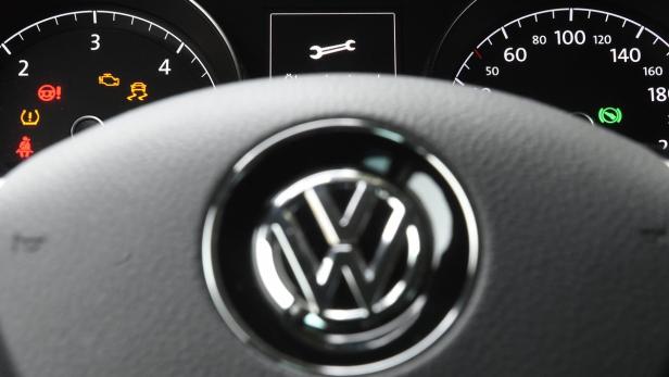 Das Armaturenbrett eines Volkswagen zeigt Warnleuchten und das VW-Logo.