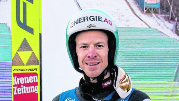 Der Skispringer Michael Hayböck vor einer Skisprungschanze.