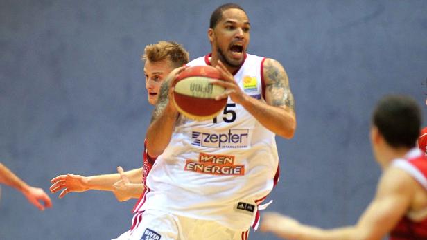 Ein Basketballspieler mit Tattoos springt mit einem Ball in der Hand.