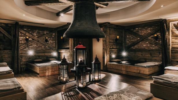Ein Ruheraum mit Holzböden, Betten und einer großen Glocke an der Decke.