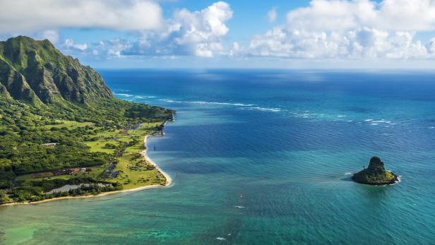 Blick auf die Küste von Oʻahu mit dem smaragdgrünen Meer und einem kleinen Inselchen.