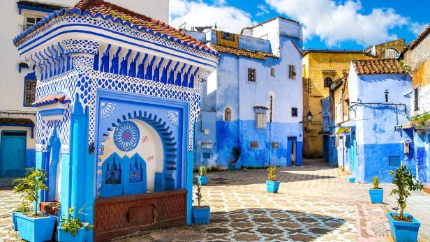 Eine blau gestrichene Straße mit einem verzierten Brunnen in Chefchaouen, Marokko.
