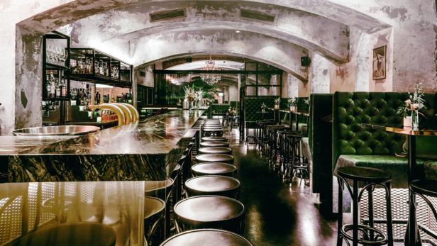 Innenansicht einer Bar mit dunklen Möbeln und einer langen Theke.