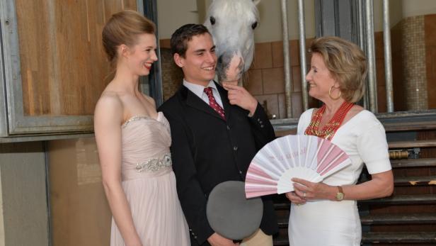 Eine junge Frau, ein junger Mann und eine ältere Dame posieren mit einem weißen Pferd im Hintergrund.