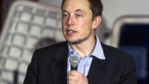 Elon Musk hält ein Mikrofon während einer Rede.