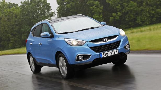 Ein blauer Hyundai ix35 fährt auf einer nassen Straße.
