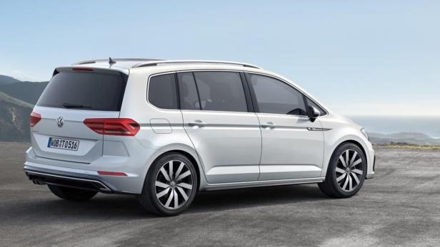 Ein weißer VW Touran steht auf einer Anhöhe.