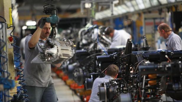Ein Arbeiter montiert ein Getriebe in einer Fabrikhalle.