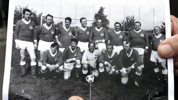 Schwarzweißfoto einer Fußballmannschaft in Trikots und Shorts mit einem Ball auf dem Rasen.