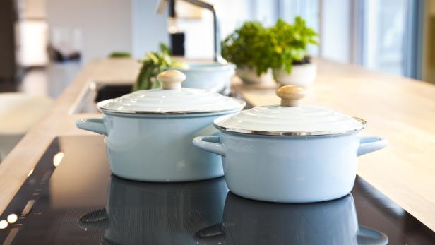 Zwei hellblaue Kochtöpfe stehen auf einem modernen Induktionskochfeld.