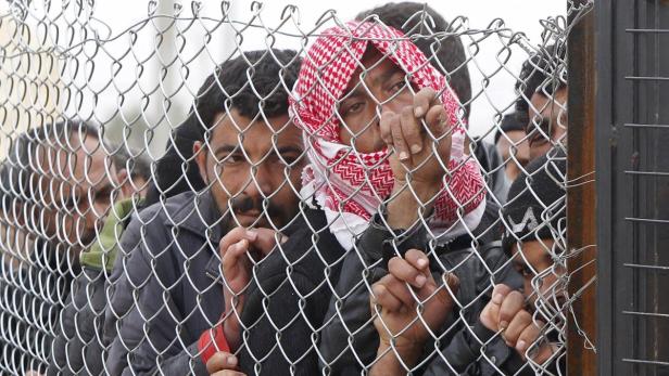 Syrische Flüchtlinge hinter dem Zaun eines Flüchtlingscamps.