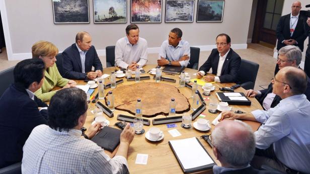 Britain&#039;s Prime Minister David Cameron (C) sits with U.S. President Barack Obama (CENTRE R), French President Francois Hollande (CENTRE 2nd R), Russian President Vladimir Putin (CENTRE L), German Chancellor Angela Merkel (CENTRE 2nd L), and other G8 leaders, during the second Plenary Session of the G8 Summit, at Lough Erne, near Enniskillen, in Northern Ireland June 18, 2013. REUTERS/Jewel Samad/Pool (NORTHERN IRELAND - Tags: POLITICS BUSINESS)