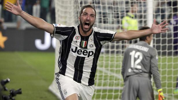 Ein Fußballspieler im Trikot von Juventus Turin jubelt mit ausgestreckten Armen.