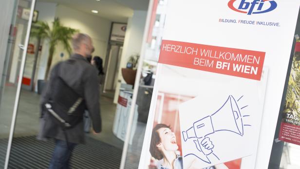 Ein Mann betritt das BFI Wien, im Vordergrund ein Schild mit der Aufschrift „Herzlich Willkommen“.