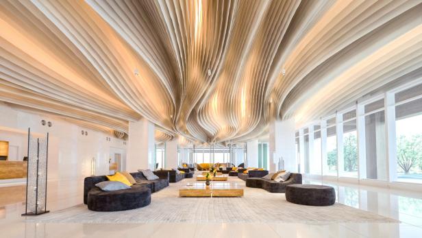 Eine Hotellobby mit geschwungenen Deckenpaneelen und modernen Möbeln.