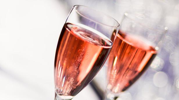 Zwei Gläser mit rosafarbenem Sekt stehen auf einem Tisch.