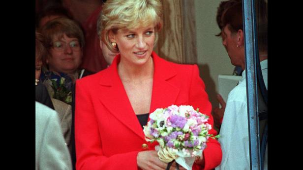 Diana, Prinzessin von Wales, in einem roten Kostüm mit Blumenstrauß und Handtasche.