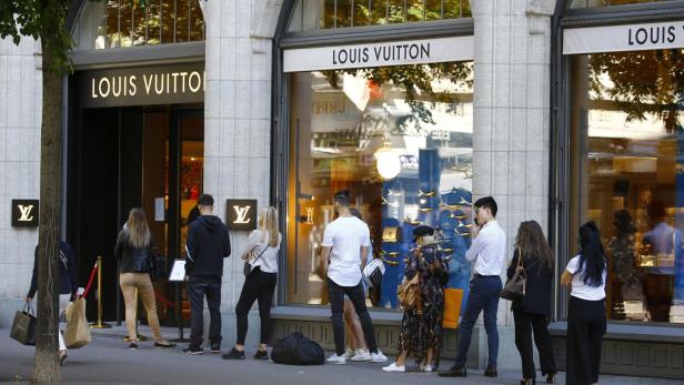 People queue in front of a shop of French luxury fashion brand Louis Vuitton in Zurich