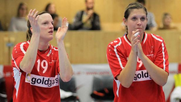 Zwei Handballspielerinnen in roten Trikots klatschen in die Hände.