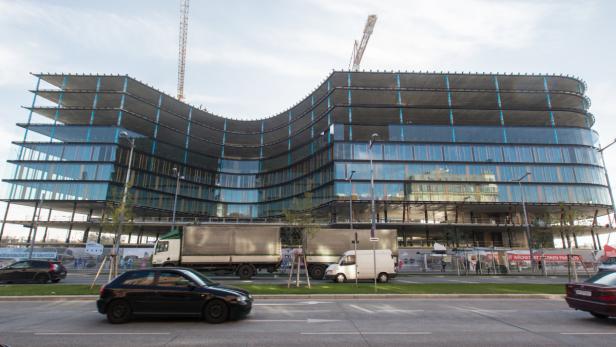 Ein modernes Bürogebäude mit geschwungener Fassade unter blauem Himmel.
