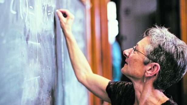 Mathemathics professor at chalkboard writing formula