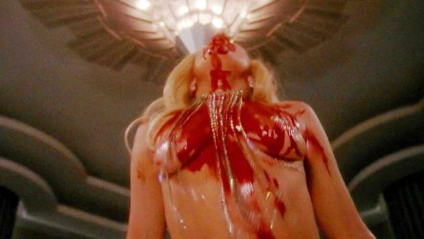 Eine Frau mit blonden Haaren ist mit Blut bedeckt.