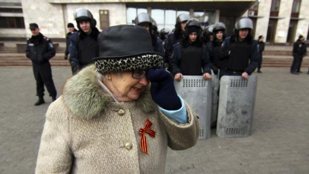Eine Frau mit einem Sankt-Georgs-Band – ein russisches Symbol militärischer Tapferkeit – vor der Regionalverwaltung in Donezk