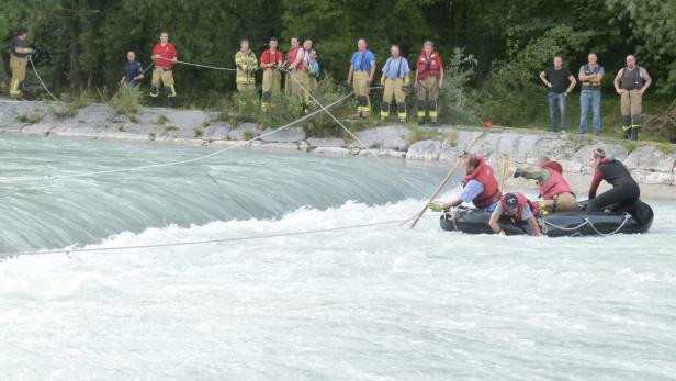 Rettungskräfte üben mit einem Schlauchboot in einem reißenden Fluss.