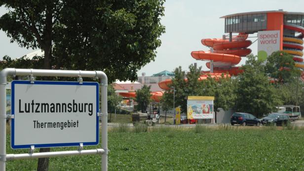 Ein Schild mit der Aufschrift „Lutzmannsburg Thermengebiet“ vor dem Hintergrund der Sonnentherme Lutzmannsburg.
