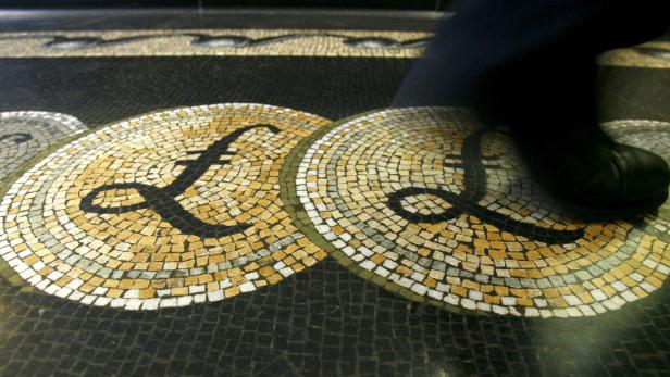 FILE PHOTO: An employee walks over a mosaic depicting pound sterling symbols on the floor of the front hall of the Bank of England in London
