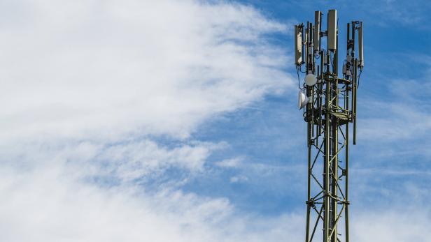 Ein Mobilfunkmast steht vor einem blau-weissen Himmel.