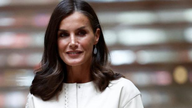 Königin Letizia trägt ein weißes Kleid und eine rote Handtasche.