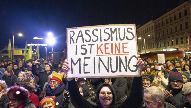 Ein Mann hält bei einer Demonstration ein Schild mit der Aufschrift „Rassismus ist keine Meinung“ hoch.