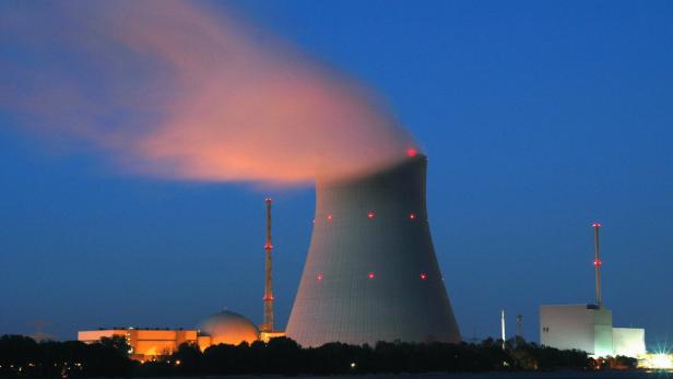 Ein Atomkraftwerk mit einem Kühlturm bei Dämmerung.