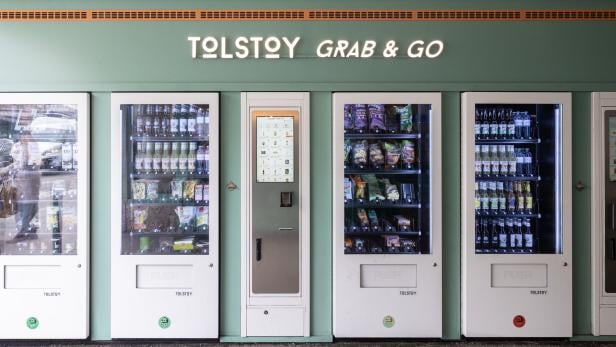 Mehrere „Tolstoy Grab & Go“-Verkaufsautomaten mit Getränken und Snacks.