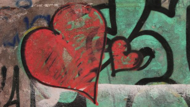 Graffiti mit zwei roten Herzen auf einer Betonwand.