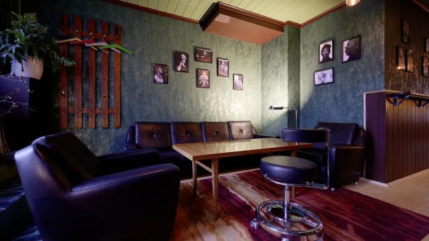 Ein Wohnzimmer mit Ledersofa, Sessel und einem Holztisch auf einem gemusterten Teppich.