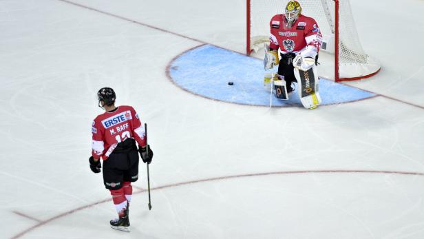 Ein Eishockeyspieler mit der Nummer 12 steht vor dem Torwart auf dem Eis.